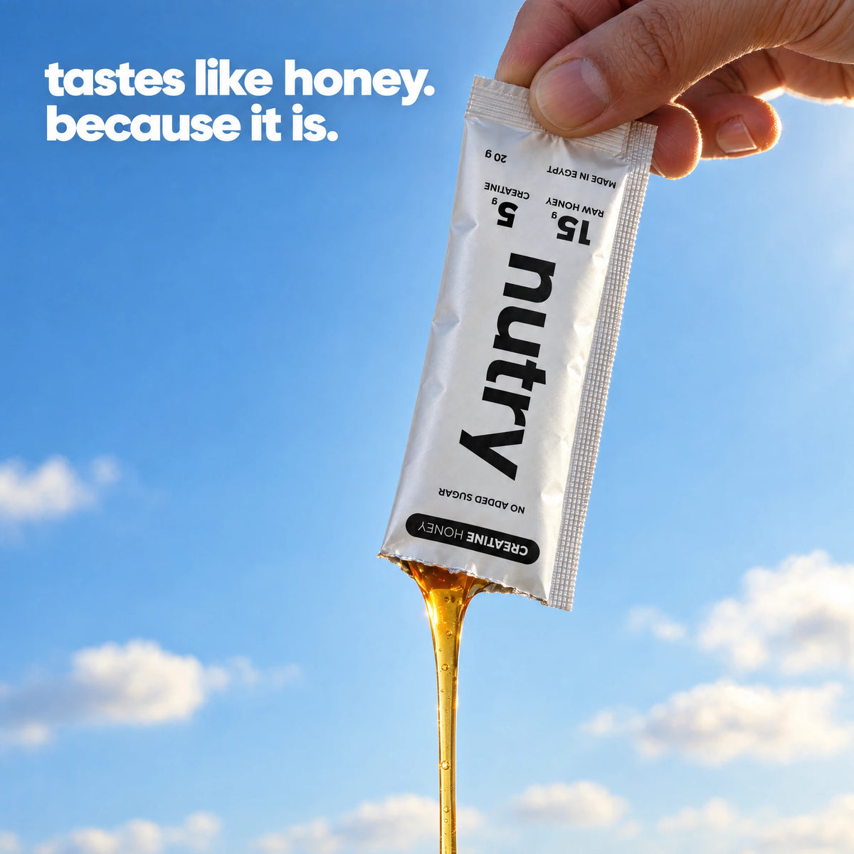 Tastes like honey, because it is: raw honey pouring from a torn Nutry Creatine Honey sachet held up against a blue sky